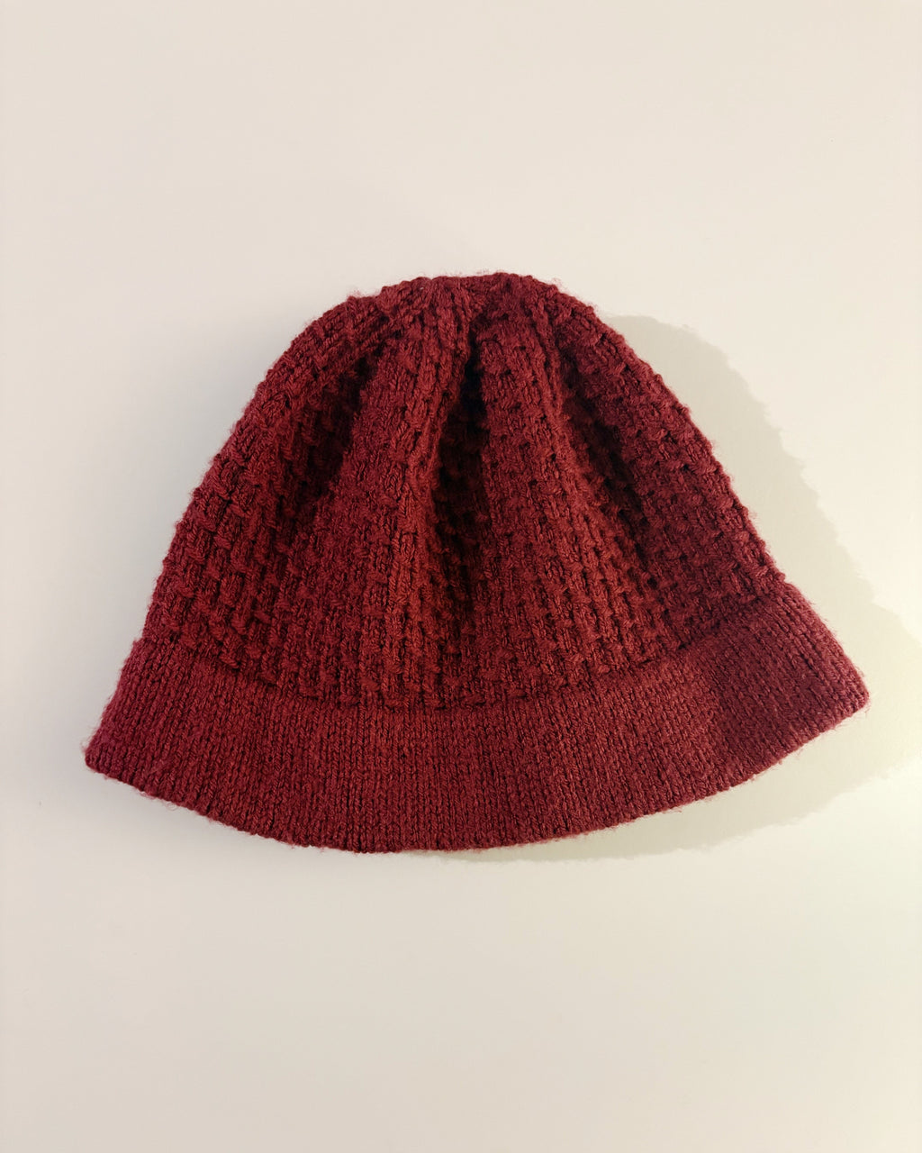 Red knitted beanie on a light beige background