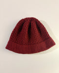 Red knitted beanie on a light beige background